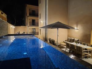 a swimming pool with a table and an umbrella at Hôtel Casa Mea in Bastia