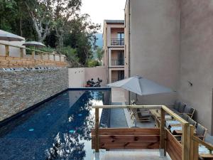 a swimming pool with an umbrella and chairs and a table and an umbrella at Hôtel Casa Mea in Bastia