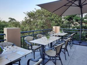 a row of tables and chairs on a balcony with an umbrella at Hôtel Casa Mea in Bastia