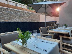 a table with glasses and an umbrella on a patio at Hôtel Casa Mea in Bastia