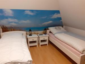 two beds in a room with a mural of the ocean at Bi Grete tohuus in Dornum