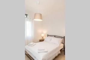 a bedroom with a bed with white sheets and a lamp at Marble Art Villas in Panormos +43 photos