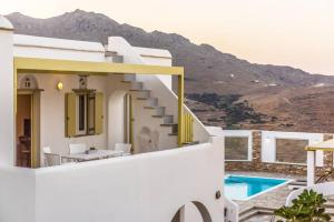 a white house with a staircase and a swimming pool at Marble Art Villas in Panormos