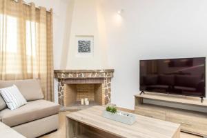 a living room with a television and a fireplace at Marble Art Villas in Panormos