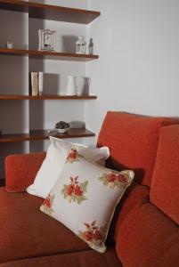 Un sofá rojo con una almohada floral. en El balcón de Padrón, en Padrón