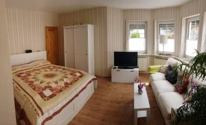 a bedroom with a bed and a couch and a television at Zum Bachhexje in Alken