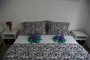 a bed with a black and white comforter and purple flowers on it at Apartman Karganovic in Višegrad