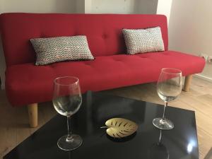 eine rote Couch mit zwei Weingläsern auf dem Tisch in der Unterkunft Lovely Studio in Bourges