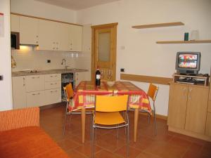 a kitchen with a table with yellow chairs and a television at Art Apartments Casa Napell in Livigno