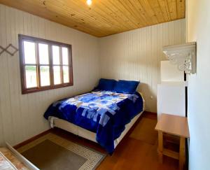 a small bedroom with a bed and a window at Casa de Campo Fazenda Kuntze in Urubici