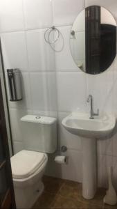 a bathroom with a toilet and a sink and a mirror at Refugio Maresias, para 10 pessoas in Maresias