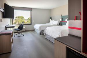 um quarto de hotel com duas camas e uma secretária em avid hotels - Madison - Monona, an IHG Hotel em Monona