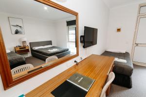 Habitación con espejo, cama y mesa. en The Ophir Hotel en Orange