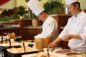two chefs standing in a kitchen preparing food at Ramada Plaza by Wyndham Jeju Ocean Front in Jeju