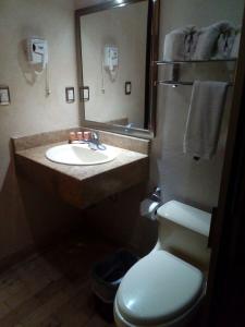 uma casa de banho com um lavatório, um WC e um espelho. em Hotel Madrid em Tuxtla Gutiérrez
