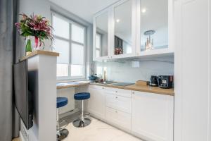 a white kitchen with white cabinets and blue stools at Apartamenty Rosa in Ustka