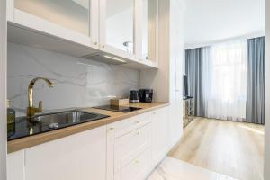 a kitchen with white cabinets and a sink at Apartamenty Rosa in Ustka