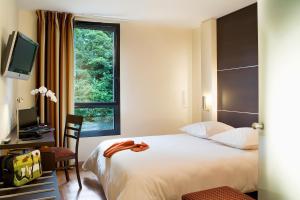 a hotel room with a bed and a window at Escale Oceania Rennes Cap Malo in La Mézière