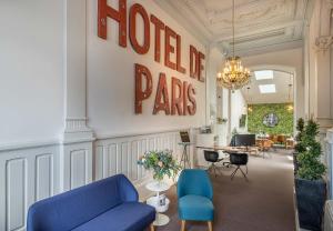リモージュにあるオテル ド パリのロビーには青い椅子2脚、壁にはホテルのページサインが付いています。