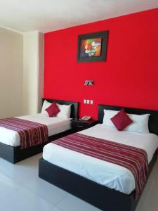 two beds in a room with a red wall at Hotel Madrid in Tuxtla Gutiérrez