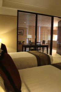 una camera d'albergo con due letti, un tavolo e una finestra di Pacific Regency Hotel Suites a Kuala Lumpur