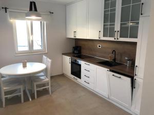 a kitchen with white cabinets and a table and a sink at Apartman Linda in Cres