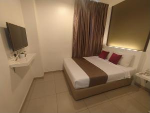a bedroom with a bed with red pillows and a television at Crescendo Boutique Hotel in Nusajaya