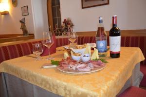 a table with two bottles and two glasses of wine at Hotel Ladina in Campitello di Fassa