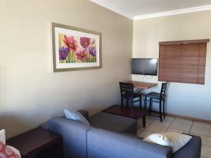 a living room with a blue couch and a desk at Grosvenor Apartments in Pretoria
