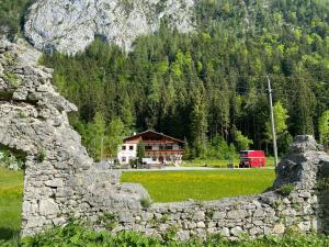 a stone wall in front of a house in a field at Bärenwirt in Leutasch