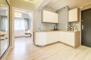 cocina con armarios blancos y suelo de madera en ApartamentyGdanske EU - Golden, en Gdansk