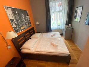 a small bed in a room with an orange wall at Central Station Studios in Prague