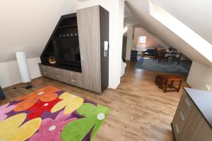 uma sala de estar com uma televisão de ecrã plano e um tapete em Ezüsthíd Hotel em Veszprém