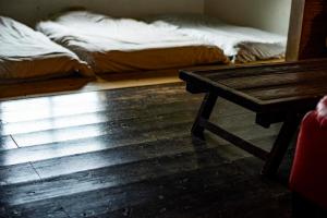 a bed sitting on top of a wooden floor next to a window at Villa SACHIIBARU in Nanjo