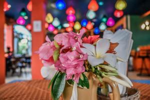 um vaso cheio de flores rosas e brancas sobre uma mesa em Sugar and Spice Inn em Kata Beach