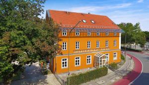 een oranje gebouw met een rood dak op een straat bij Hotel zum Fischer in Dachau