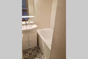 ein Badezimmer mit Badewanne und Waschbecken in der Unterkunft Les 2 alpes, charmant et authentique 4-6 personnes in Mont-de-Lans