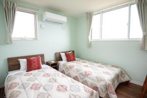 - une chambre avec 2 lits et 2 fenêtres dans l'établissement MAKAI green, à Nakijin