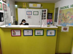 a woman wearing a mask behind a counter with signs at Diagonal House Hostel in Barcelona