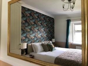um espelho que reflecte um quarto com uma cama e uma parede floral em Dalgreine Guest House em Blair Atholl