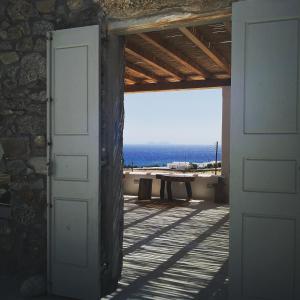 een open deur naar een patio met uitzicht op de oceaan bij M-Vibes Mykonos Suites in Kalafatis