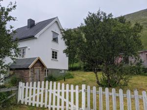 a white house with a white picket fence at North Cape family lodge in Skarsvåg