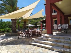 een patio met tafels en stoelen onder een parasol bij Villa Kerkyra in Gouvia