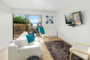 a living room with a white couch and a television at Self Contained Beach View Apartment in Kingston Beach