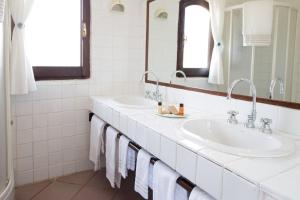 a bathroom with two sinks and a mirror at La Jacia Hotel & Resort in Baja Sardinia