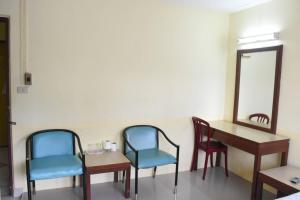 una sala de espera con 2 sillas, una mesa y un espejo en โรงแรมวัฒนาตรัง en Trang