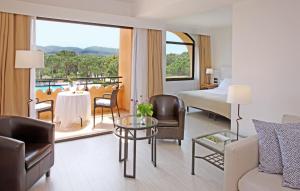 パルスにあるラ コスタ ホテル ゴルフ＆ビーチ リゾートのベッド、テーブル、椅子が備わるホテルルームです。