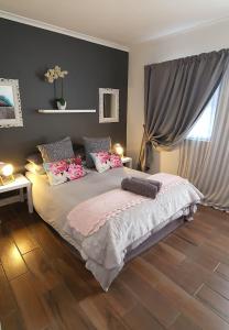1 dormitorio con 1 cama grande con almohadas rosas en Aintree Farm Cottage, en Langebaan