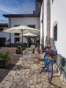 una bicicleta azul estacionada junto a un edificio con mesas y sombrillas en Casa de la Montaña Albergue Turístico en Avín