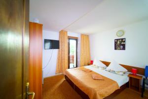 a hotel room with a bed and a television at Pensiunea Margaritar in Predeal